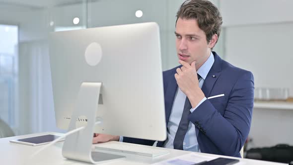 Young Businessman Thinking and Working on Desk Top 