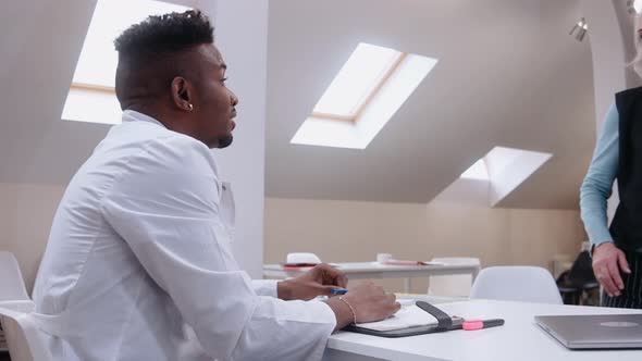 Elderly Woman Comes on Consultation with a Black Male Doctor in Bright Office