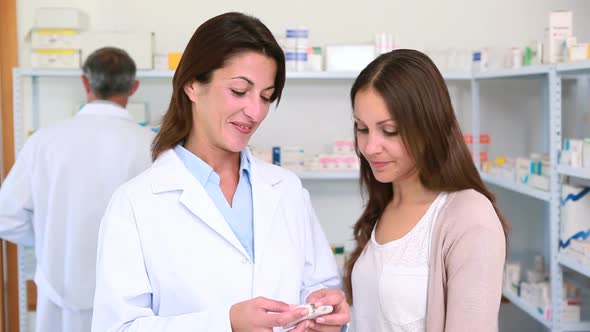 Pharmacist talking to a customer while holding pills