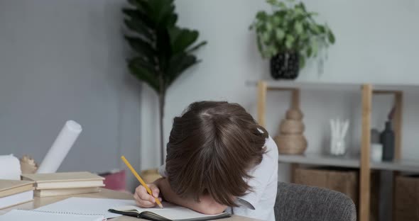 Exhausted School Kid is Tired From Homework and Learning and is Lying on the Desk