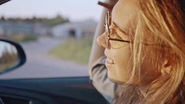 Closeup of Adorable Young Blonde Portrait Wearing Stylish Sunglasses Driving Her Car at Sunset