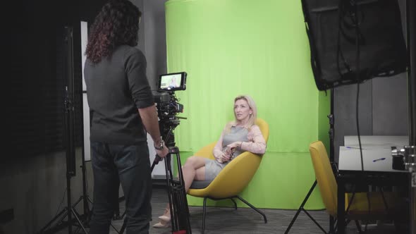 Portrait of Confident Adult Caucasian Woman Sitting on Yellow Armchair and Talking at Camera