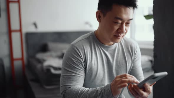 Handsome Asian man texting by phone
