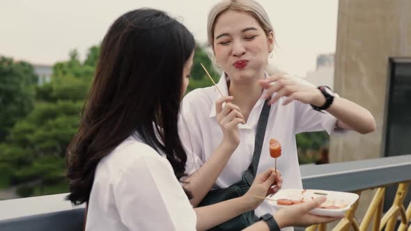 Asian lesbian couples enjoying traveling in Thailand and eating meatballs.