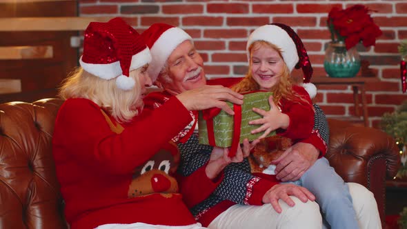 Grandparents Gifting Christmas Xmas Present Box to Amazed Happy Granddaughter at Home Celebrating