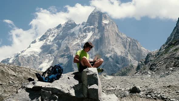 Man Tourist Freelancer Remotely Working on Nature and Using Computer in the Mountains Sitting on a