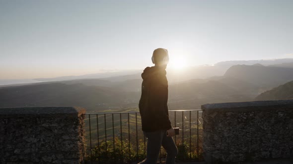 silhouette of boy walking with headphones in the mountains