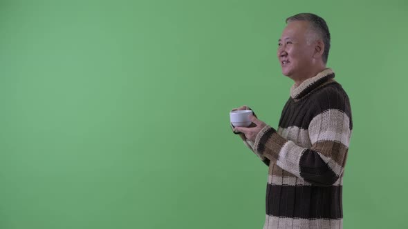 Profile View of Happy Mature Japanese Man Drinking Coffee Ready for Winter