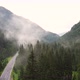 Aerial Drone Overhead of Single Car Driving Down Curvy Mountain Road Through Green Forest Valley - VideoHive Item for Sale
