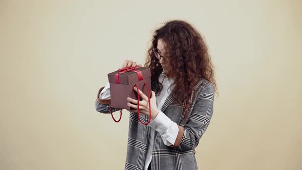 The Curious Young Woman Opens a Gift Box and Surprised By What is in the Box Smiles with Her Teeth