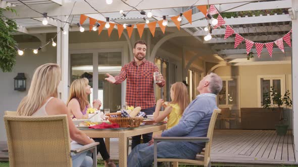 Young man taking to family members while having lunch outdoors