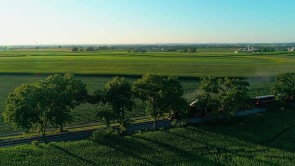 Steam Train Passing through Amish Farm Lands and Countryside on a Late Sunset Summer Day as seen by