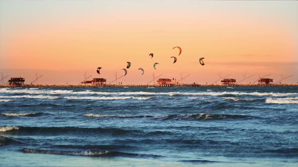 People Do Kitesurfing Above Deep Blue Ocean Waves at Sunset