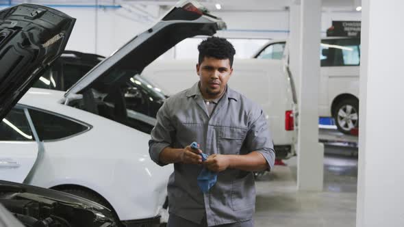 African American male car mechanic cleaning his hands with a rag and looking at the camera