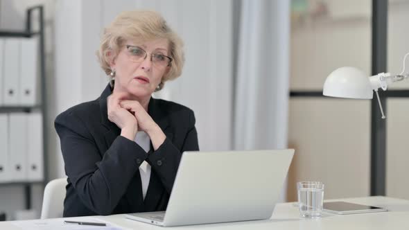 Old Businesswoman Thinking While Using Laptop at Work