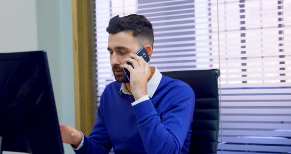 Executive talking on mobile phone at desk 