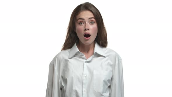 Closeup of Attractive Female Brunette in White Collar Shirt Raising Eyebrows and Gasping Surprised