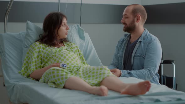 Caucasian Person with Pregnancy Sitting with Man in Hospital Ward