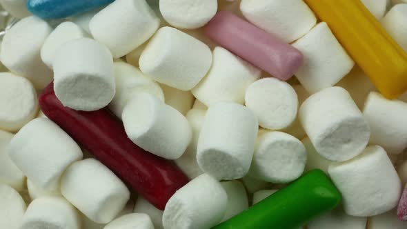 White Marshmallow Rotating With Colored Stick Sweets. Close Up