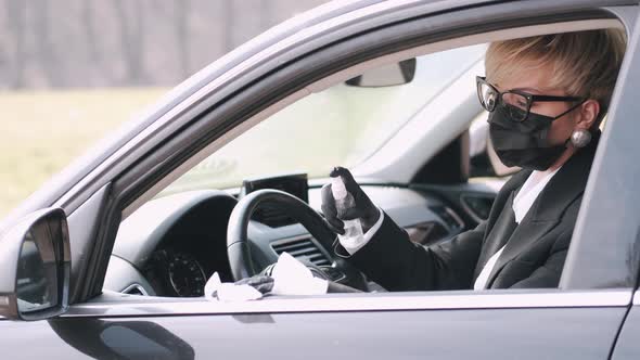 The Woman in a Disposable Mask Is Disinfecting Her Car with Antiseptic