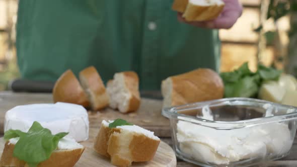 Stylish woman make a snack with bread and cheese on a table in outdoor