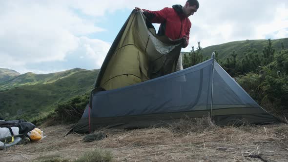 Tourist Traveler Sets Up a Single Tent in the Mountains. Hiking. Solo Tourism