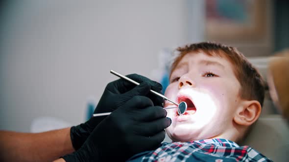 A Little Stressful Boy with Baby Teeth Having a Treatment in the Dentistry