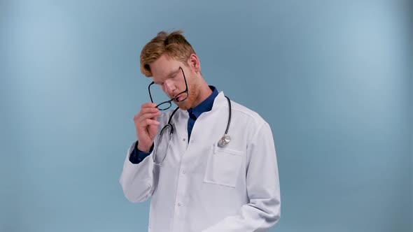 Tired Doctor Rubs His Eyes and Sighs After a Hard Work Isolated on Blue Background