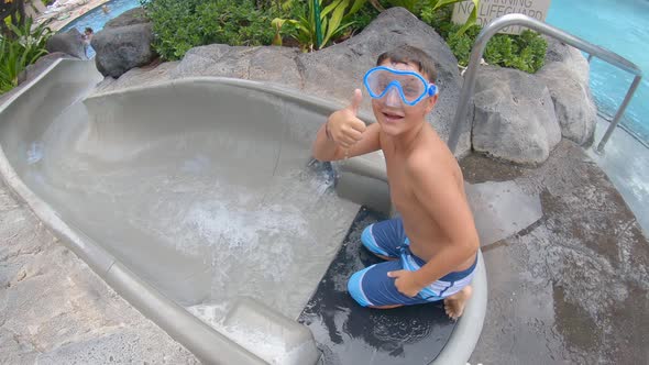 A boy plays on a waterslide water slide in a pool at a hotel resort.