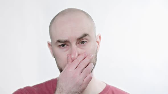 Portrait of a Bald Bearded Man Holding His Nose Against a Bad Smell