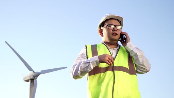 Asian Engineer with Glasses Hard Hat and Bright Vest Is Actively Discussing the Issue of Working