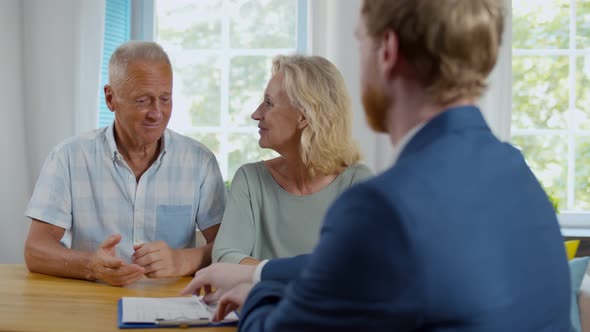 Happy Senior Couple Sign Document at Meeting with Financial Advisor