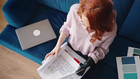 View From Above of an Redhaired Young Girl Interior Designer Working with Drawings Using a Robotic