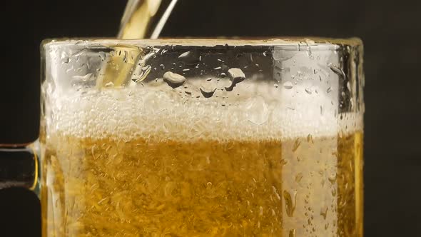 Close up background of pouring beer with bubbles and foam in glass