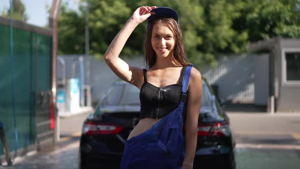 Portrait of Beautiful Confident Young Slim Woman Putting on Cap in Slow Motion Looking at Camera