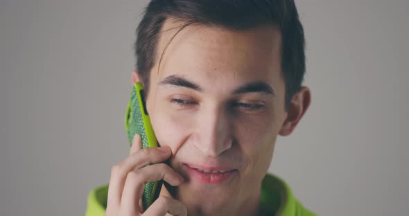 Closeup Smiling Young Handsome Man Speaking Phone Emotionally at Grey Wall Background