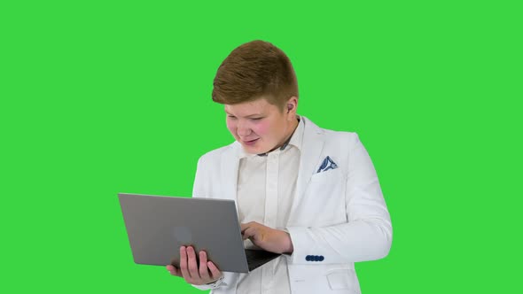 Caucasian Boy in a Suit Working on Laptop on a Green Screen Chroma Key