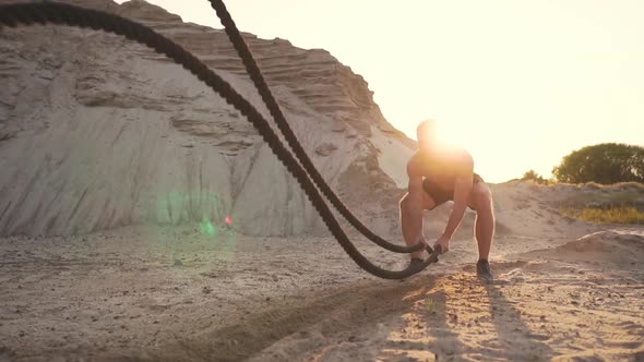 Male Athlete push-UPS on the Beach and Hits the Ground with a Rope, Circular Training in the Sun