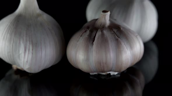 Closeup of Organic Three Heads of Garlic on a Table Isolated on a Dark Background