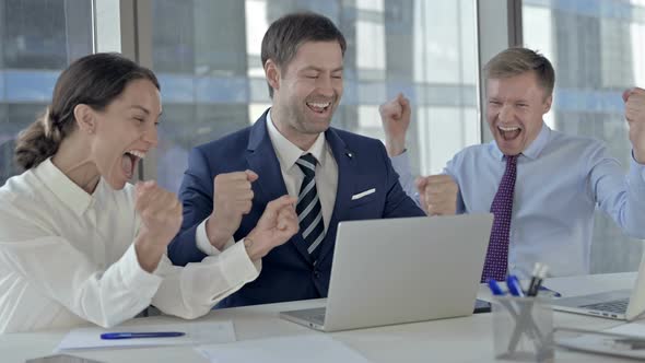 Executive Business People Celebrating Success and Using Laptop on Office Table