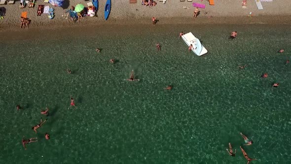 Girl goes swimming into the clear sea water. Summer beach, people, sand and water.