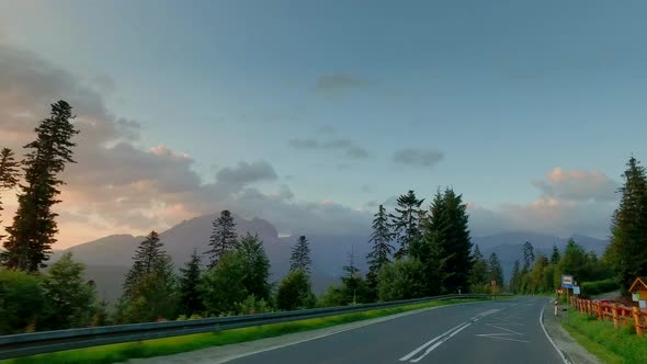 Driving a car on the road between the mountains in the Tatras at sunrise