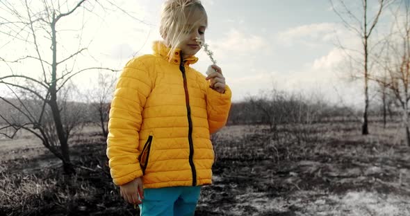 A small child dressed in the colors of the Ukrainian flag smells a flower.