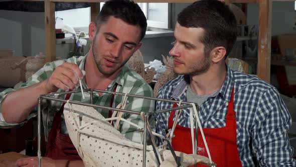 Two Male Sculptors Decorating Statue at Their Workshop