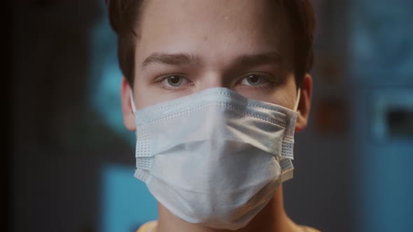 Portrait of Young Man with Light Blue Eyes Wearing Medical Protective Mask for Prevention