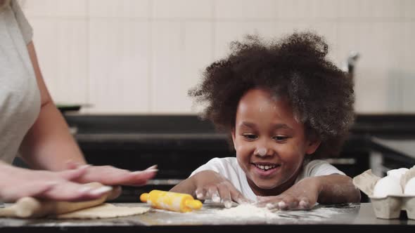 Black Little Girl with Her Mother in the Kitchen  the Girl Playing with Flour