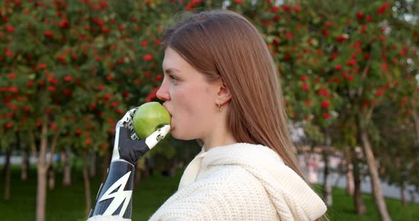 Portrait of a Girl Who Eats an Apple with a Bionic Hand