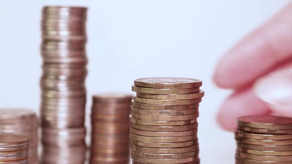 A woman's hand puts coins in a column. Investment concept. Metallic currency