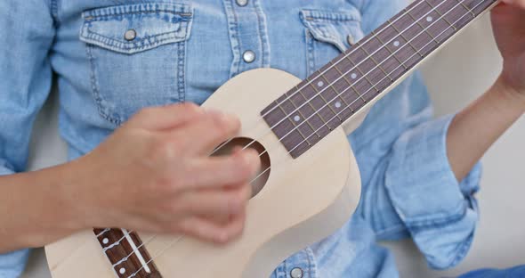 Woman play ukulele at home