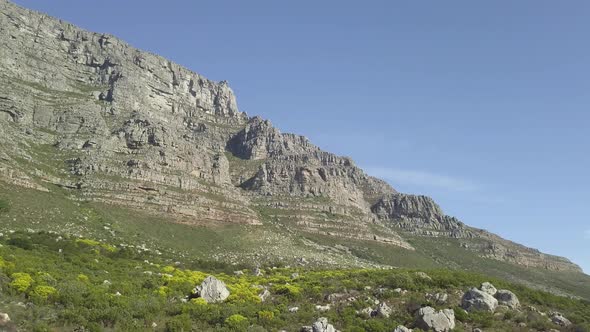 Aerial lower angle scenic drone flight pan shot. View of Table Mountain in late afternoon sun agains